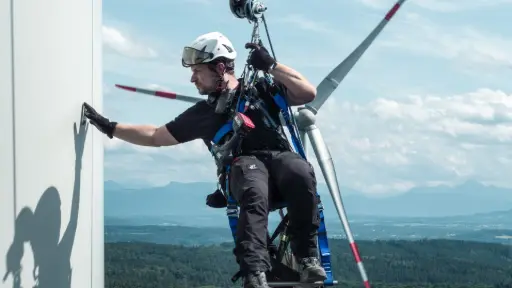 Un homme suspendu à une éolienne